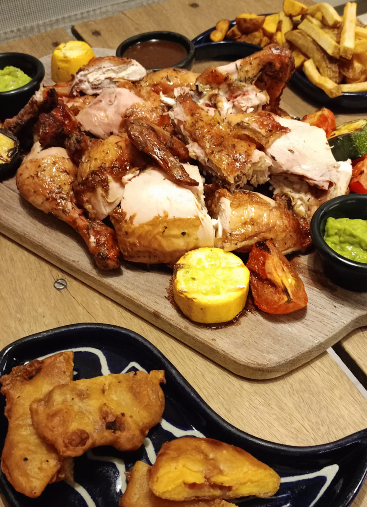 Barrilada del Parche en Las Puertas Chía: pollo entero asado al barril con papa dorada, tomates, ají y salsas de la casa sobre tabla de madera, para compartir entre 3 y 6 amigos en septiembre