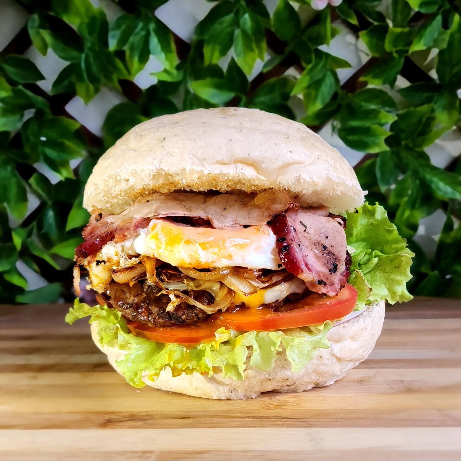 Hamburguesa La Balsa de Las Puertas Chía con huevo frito, tocineta y vegetales frescos sobre tabla de madera